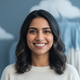 Headshot of a smiling South Asian woman in her late 20s or early 30s looking at the camera.